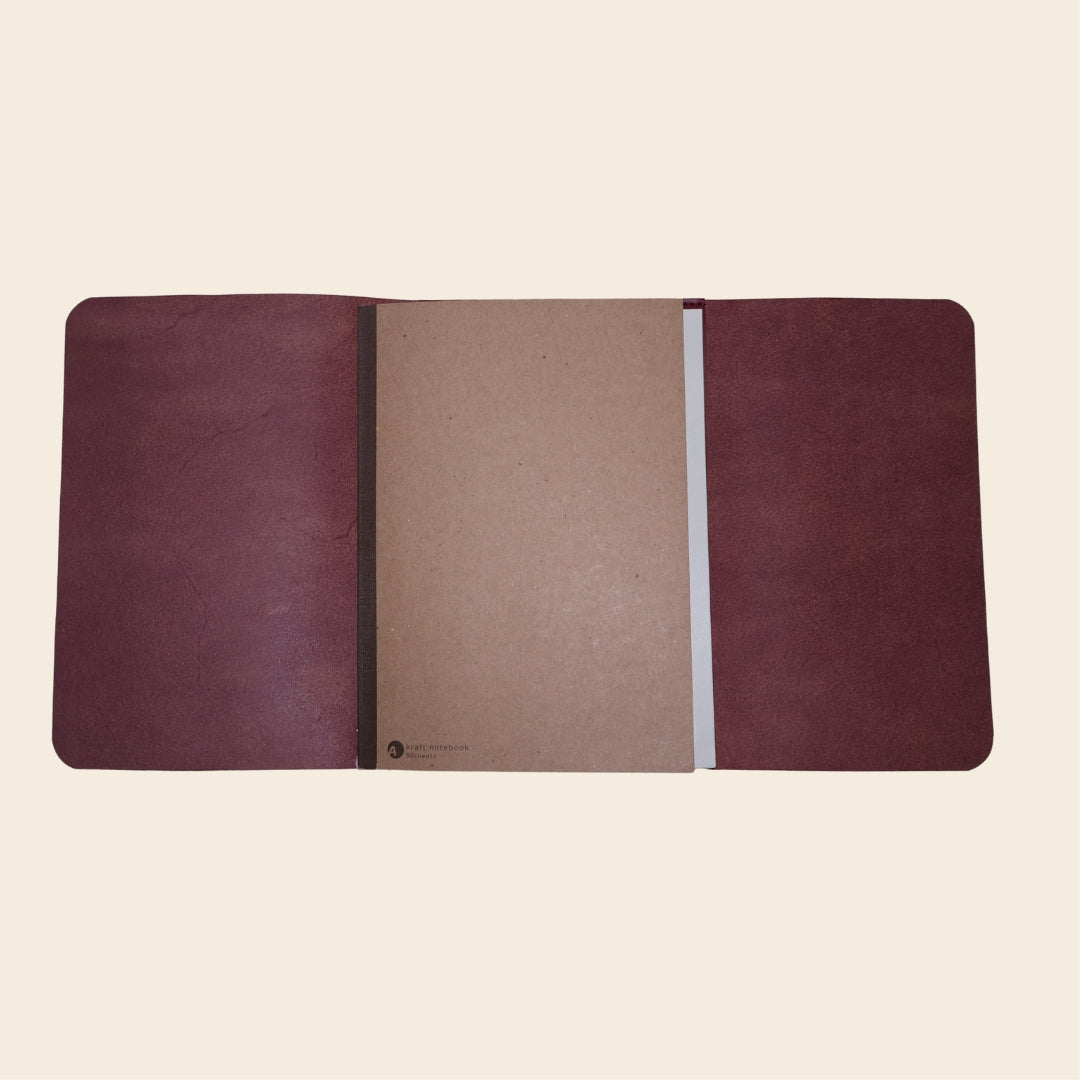 Open maroon journal with a notebook on a beige background