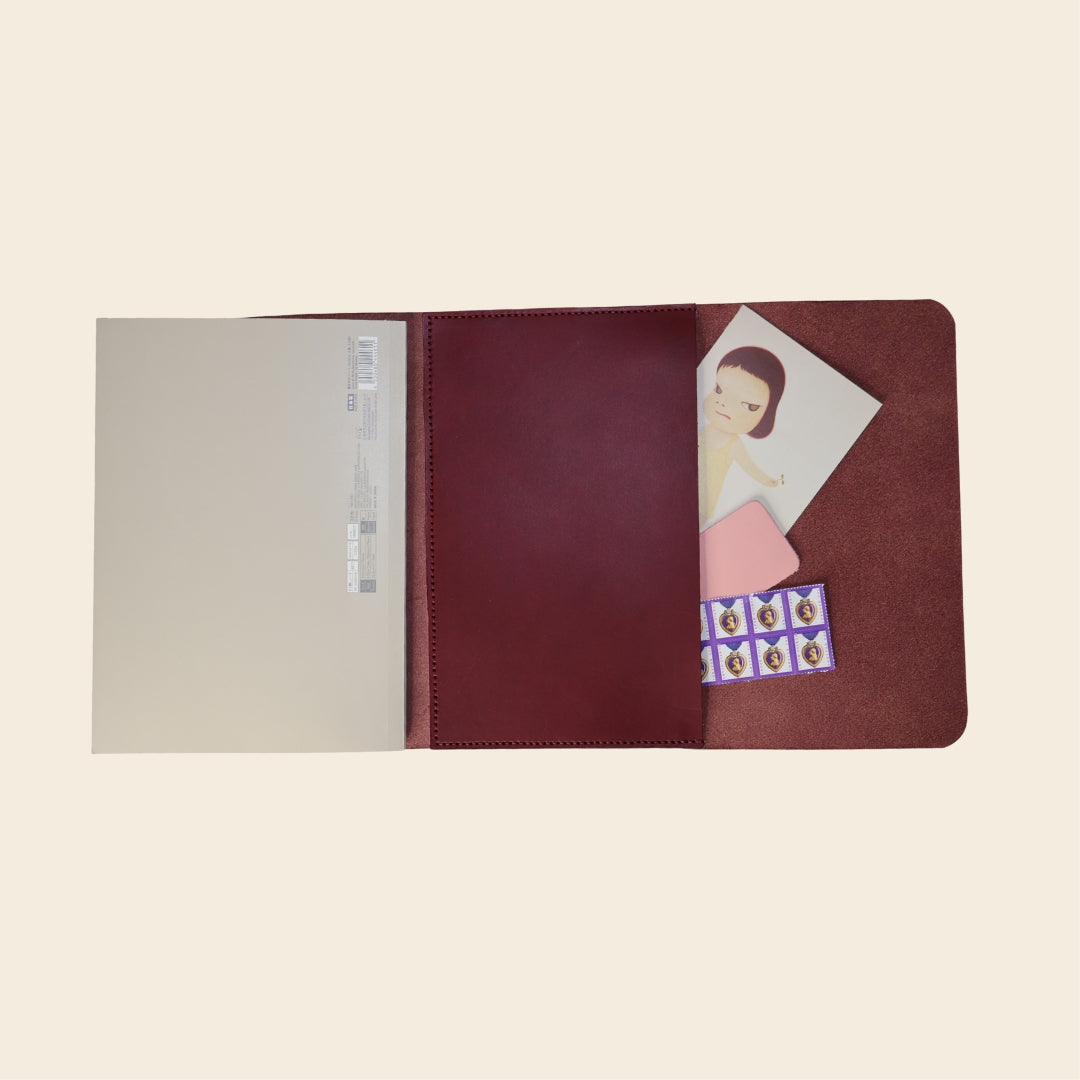 Maroon notebook with a character illustration on a beige background