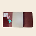 Brown leather journal with a card and pink stickers on a beige background