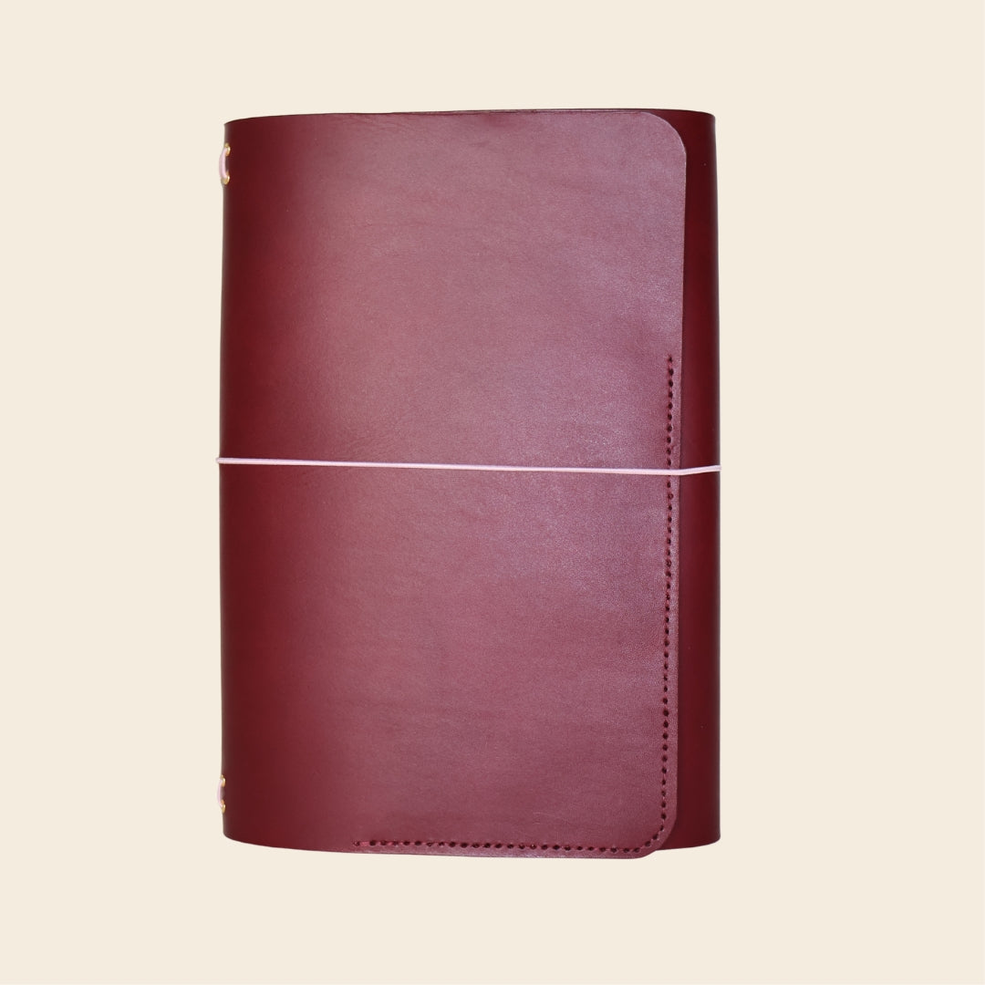 Maroon leather notebook on a beige background