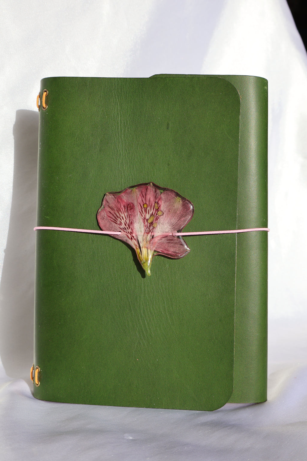 Green leather clutch with a pink flower on a white background