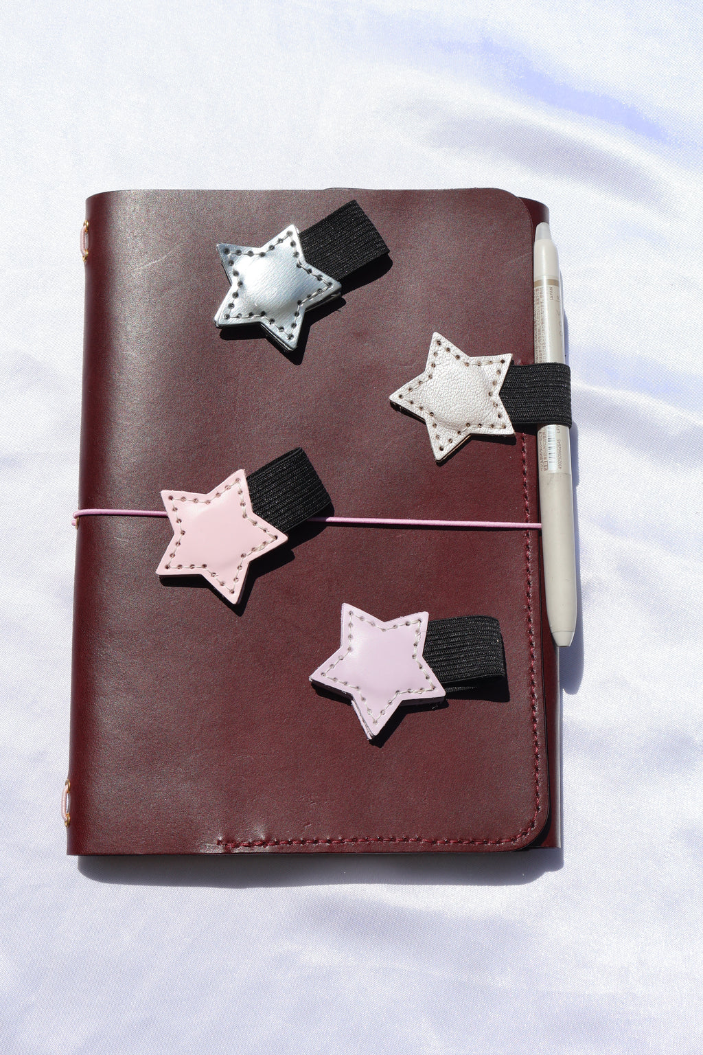Star-shaped bookmarks on a leather-bound notebook with a white background
