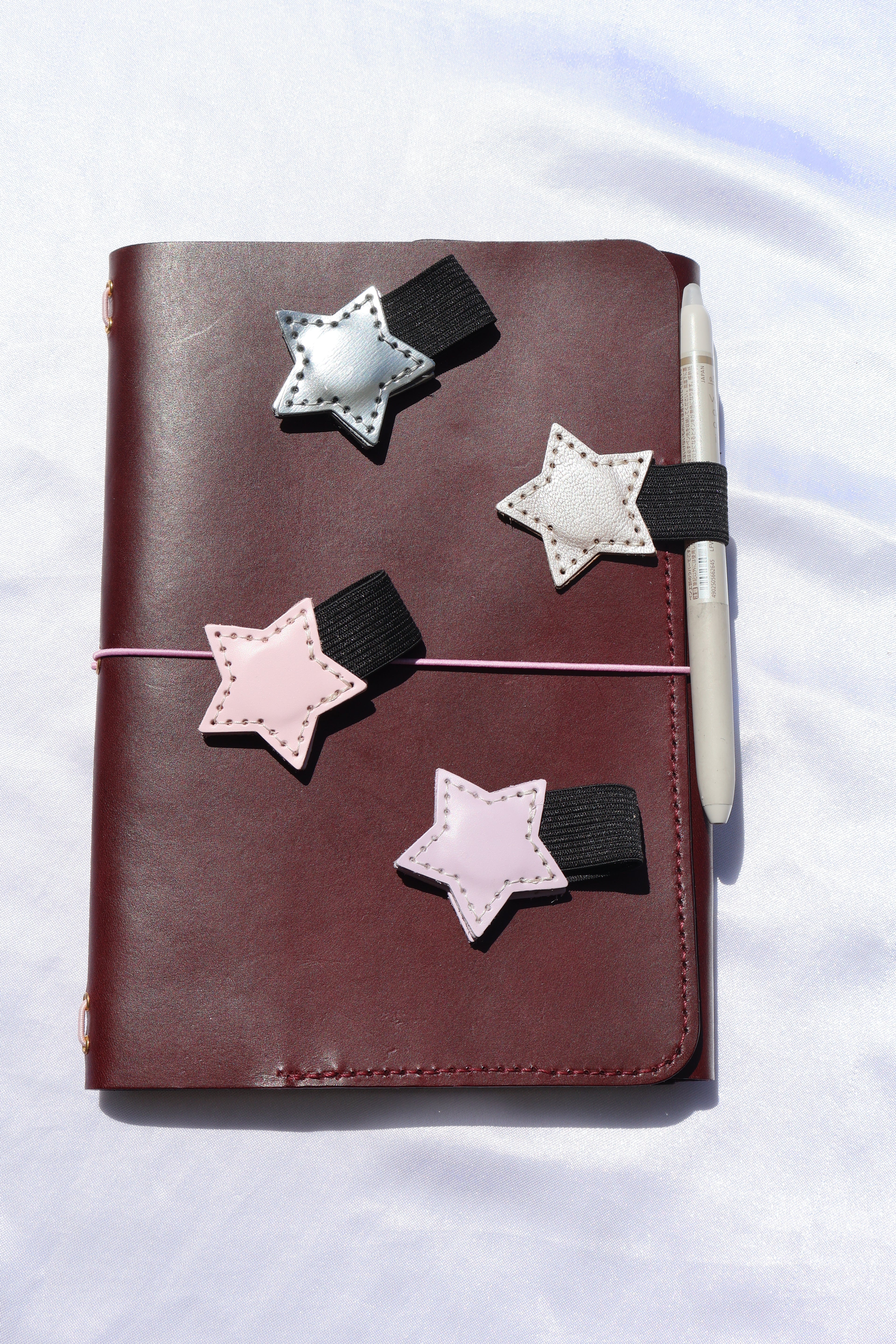 Star-shaped bookmarks on a leather-bound notebook with a white background