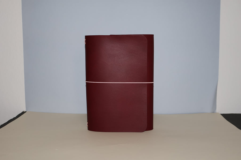 Maroon leather-bound book on a beige surface with a light gray background
