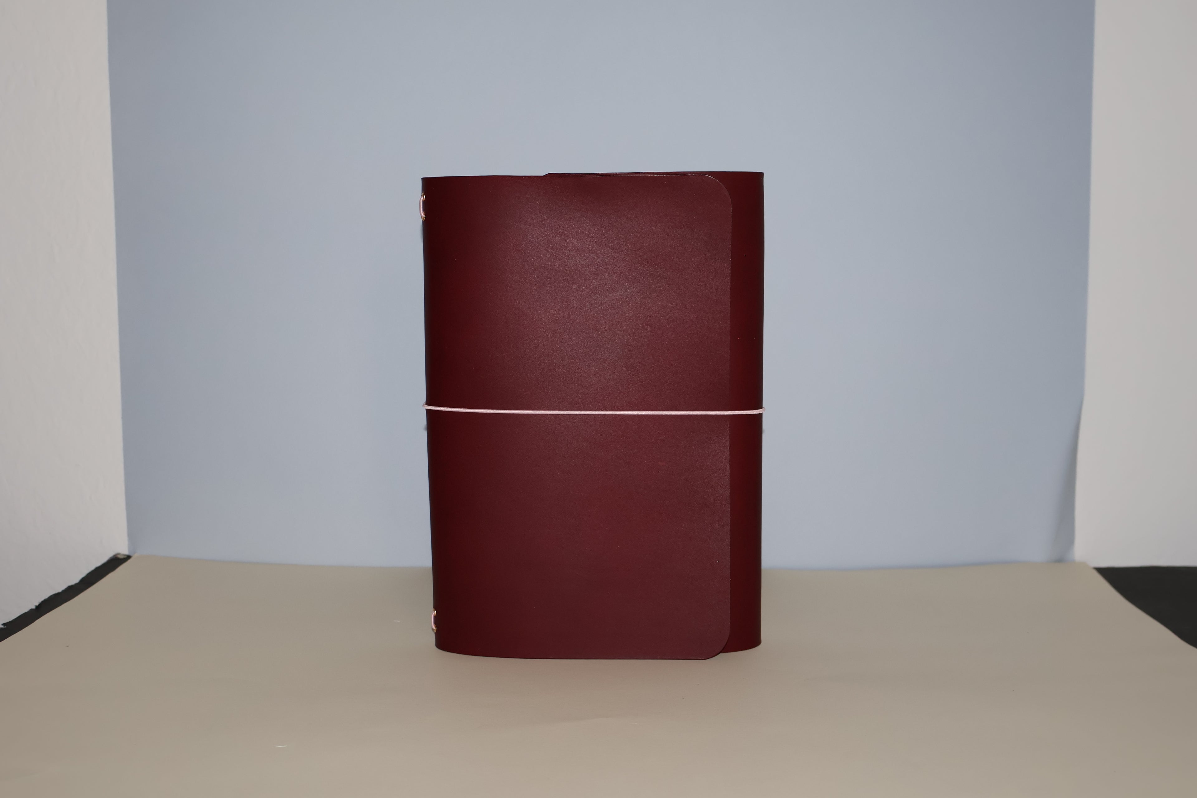 Maroon leather-bound book on a beige surface with a light gray background