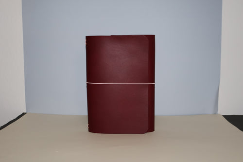 Maroon leather-bound book on a beige surface with a light gray background