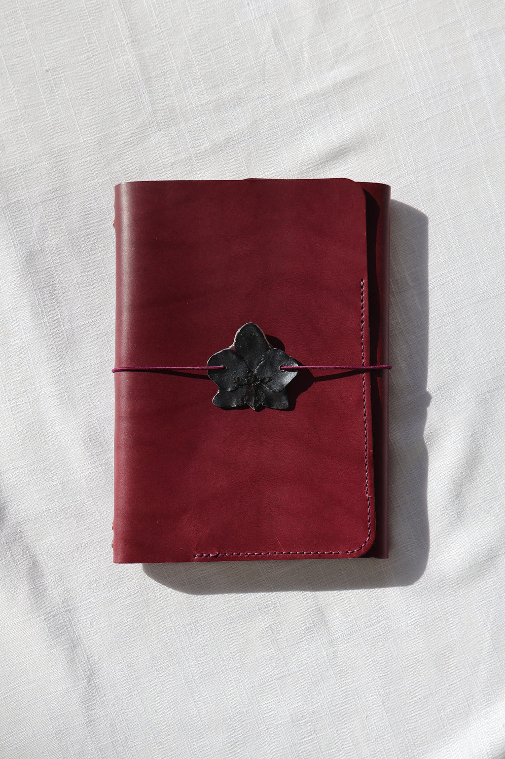 Red leather wallet with a black buckle on a white fabric background