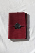 Red leather wallet with a black buckle on a white fabric background
