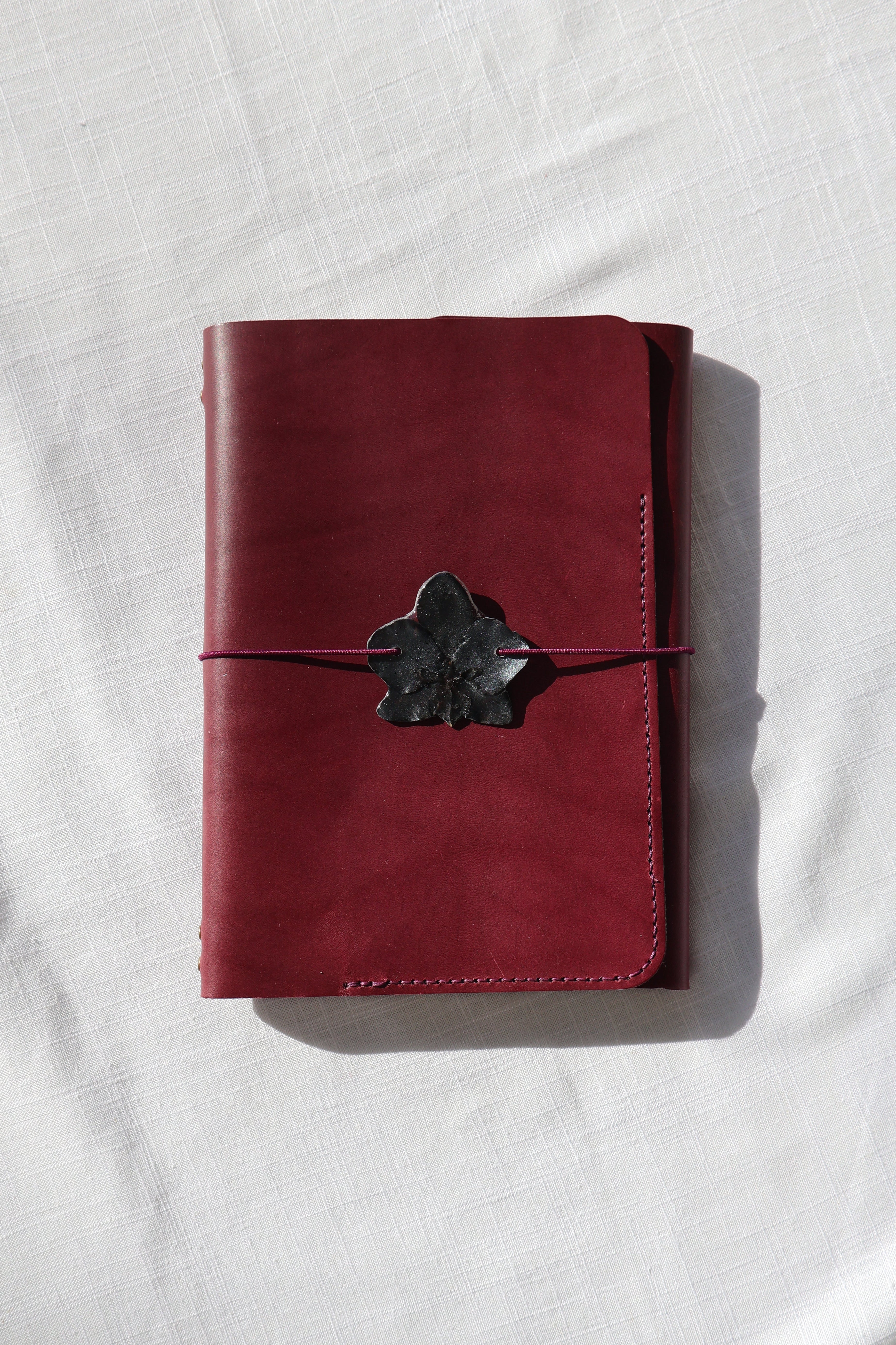 Red leather wallet with a black buckle on a white fabric background