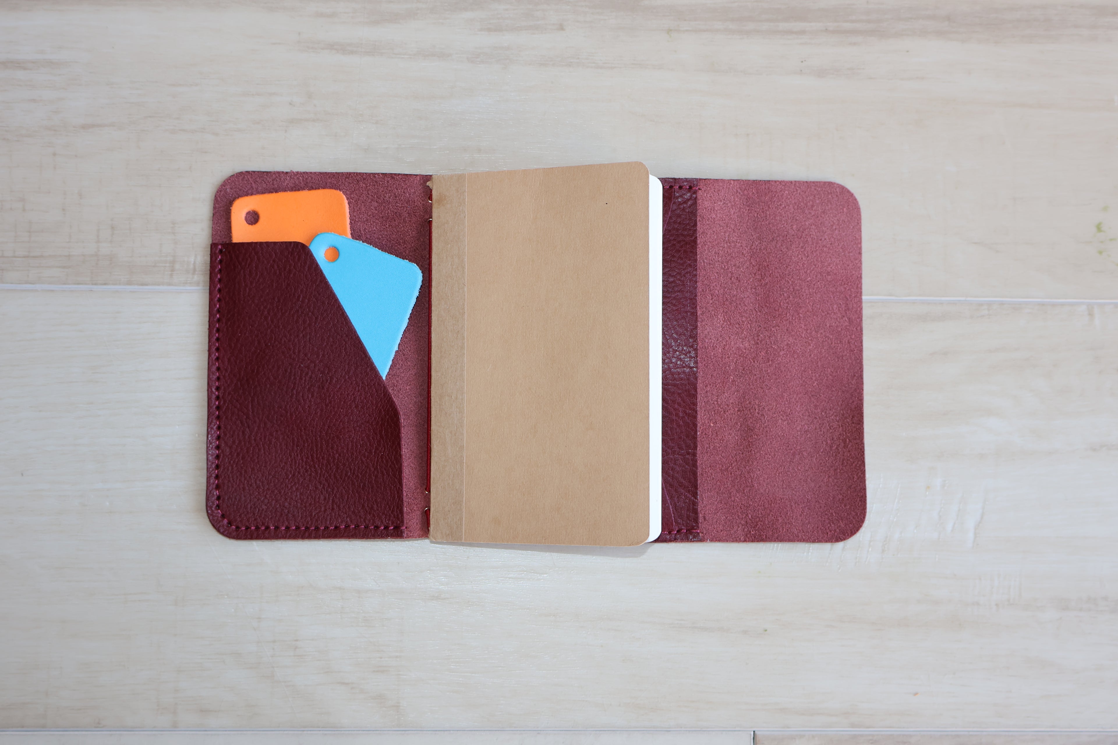 Open leather notebook with colorful pages on a wooden surface