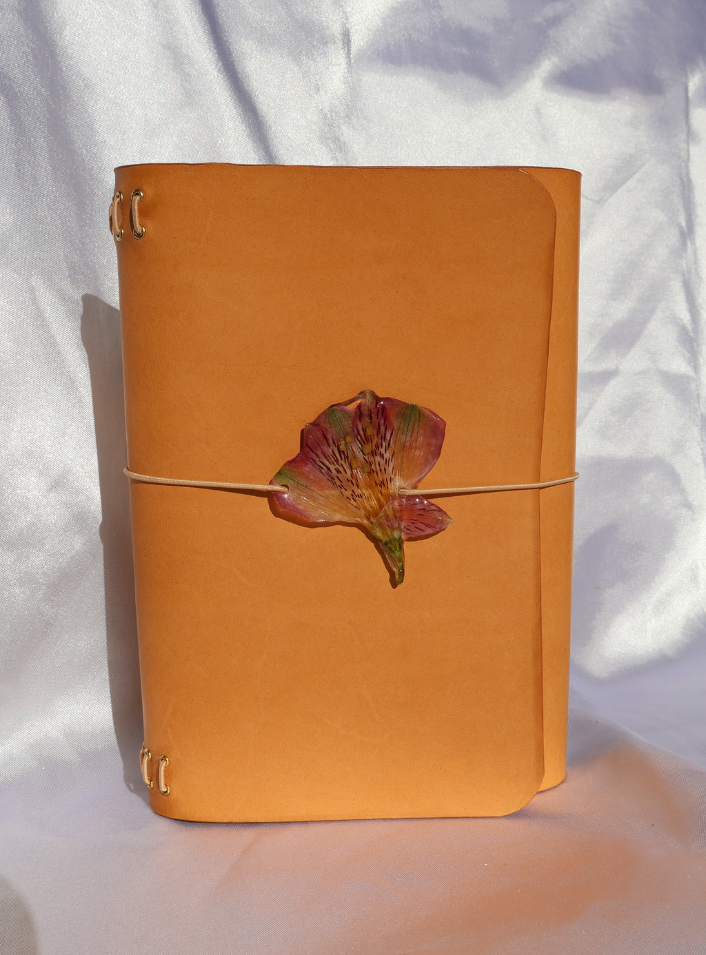 Orange leather notebook with a leaf design on a white fabric background