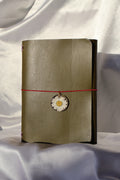 Folded paper with a decorative flower and red string on a white fabric background