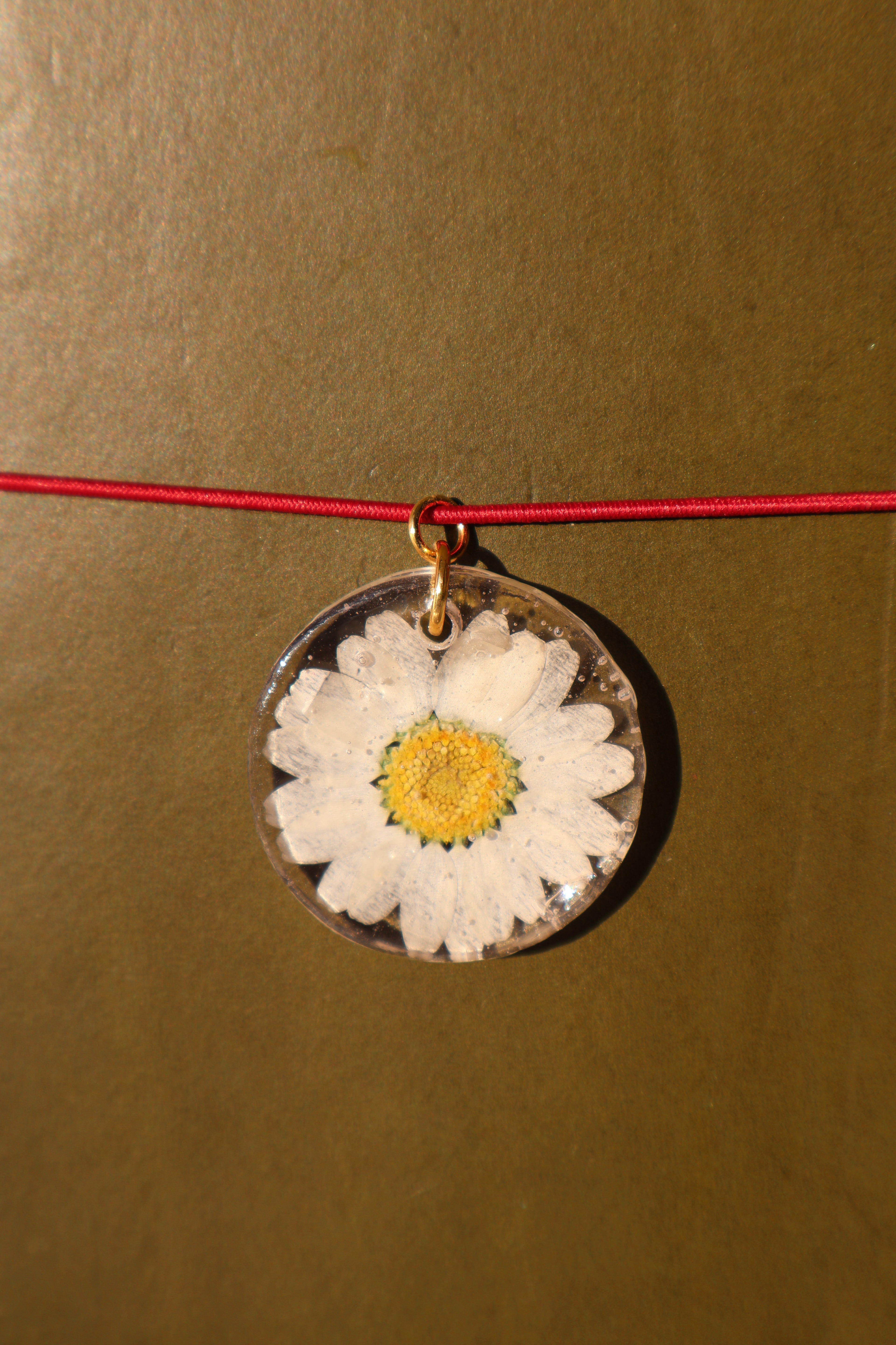 Necklace with a pendant featuring a pressed flower on a beige background