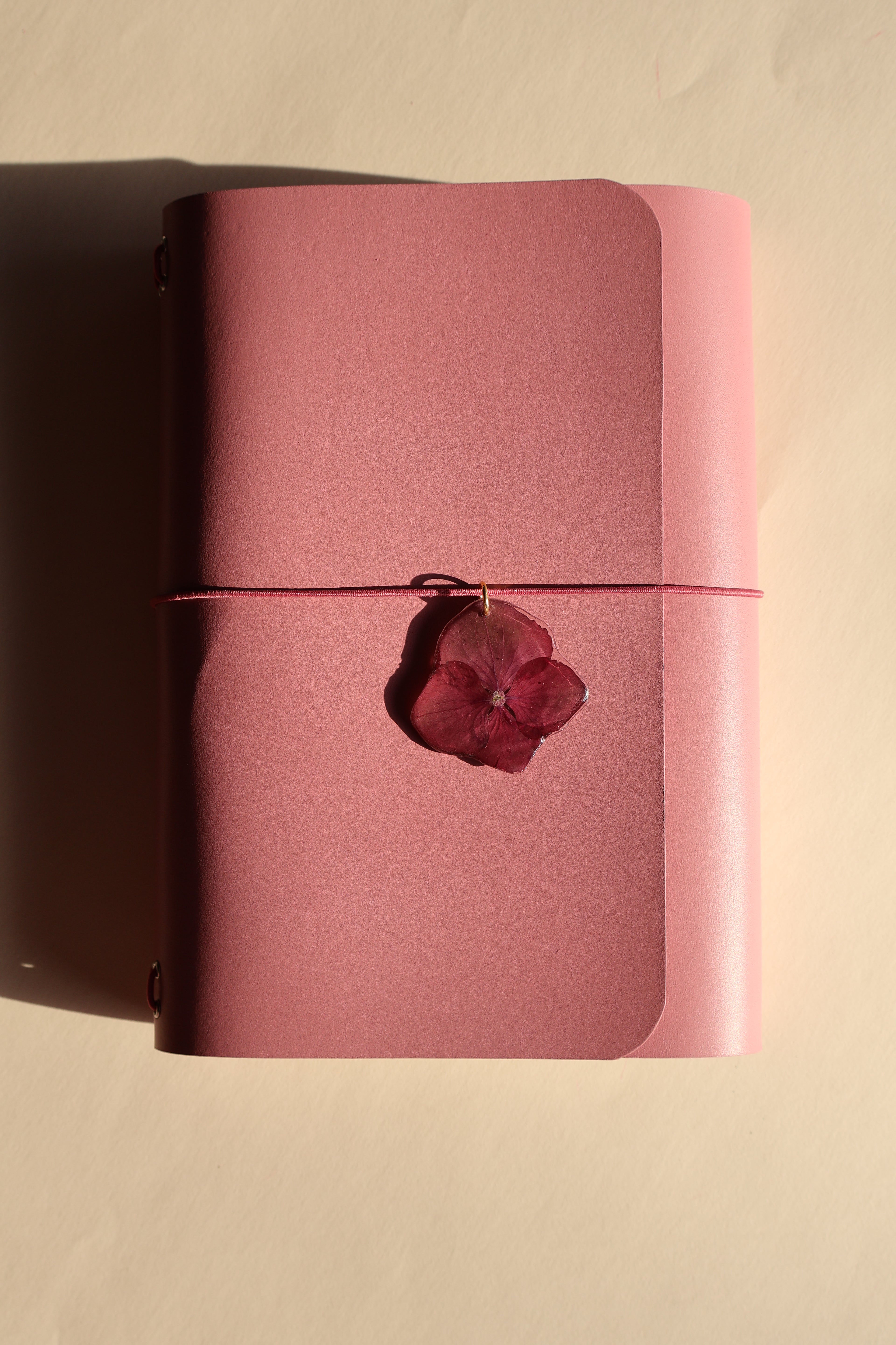 mauve journal with a red flower on a beige background