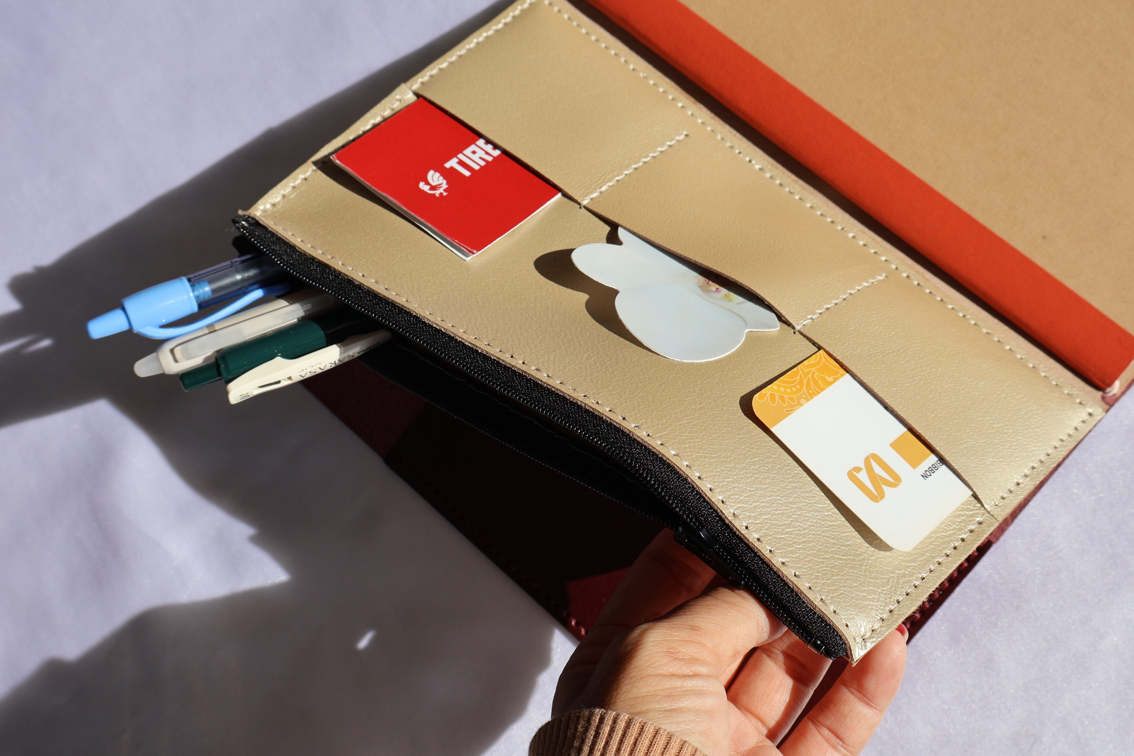Beige wallet with card slots and a hand holding it