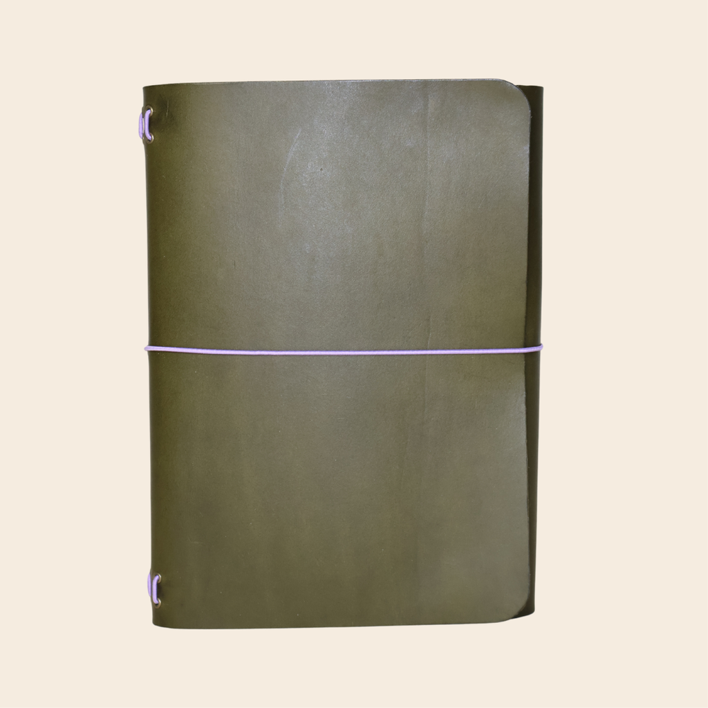 Green leather notebook with a purple elastic band on a beige background