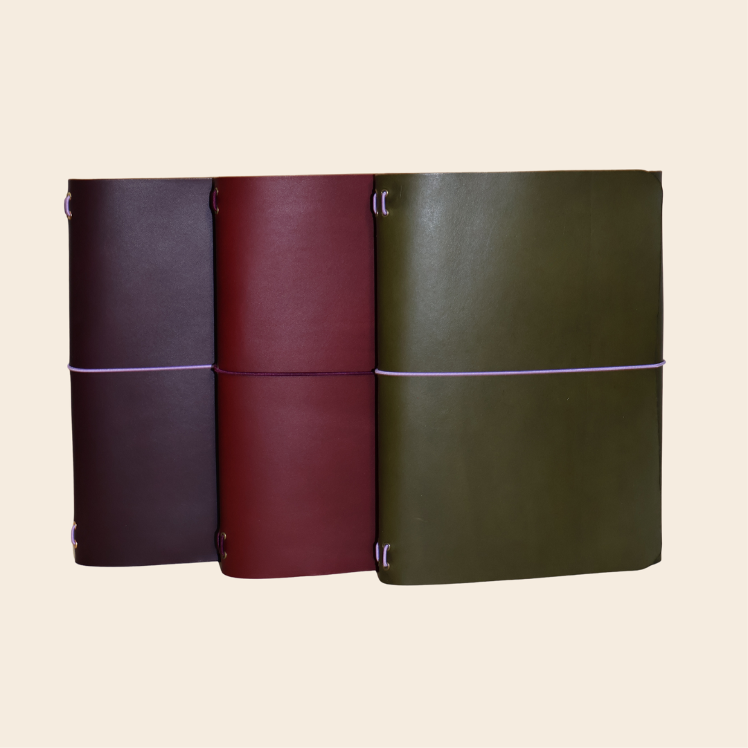Three leather-bound books in different colors on a beige background