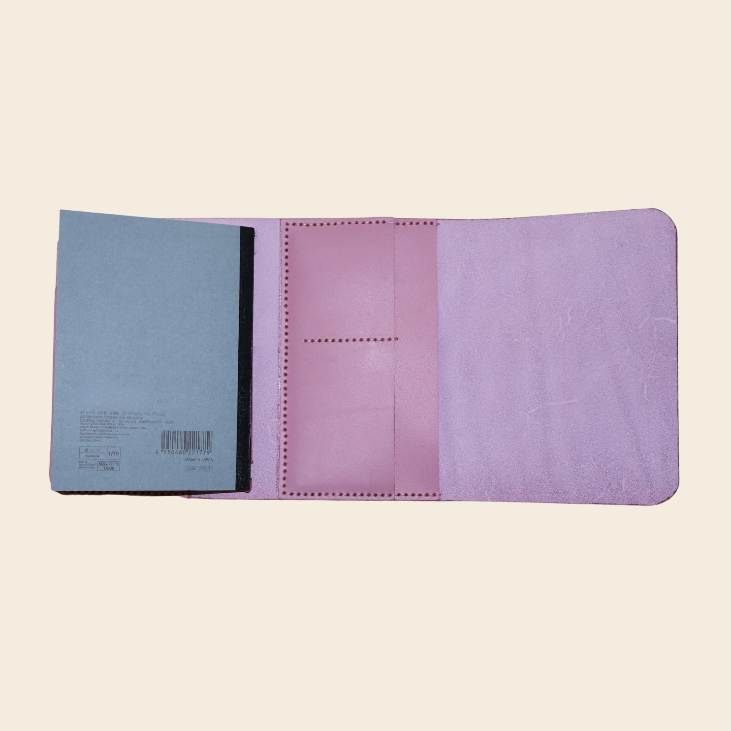Open mauve journal with a blue notebook on a beige background
