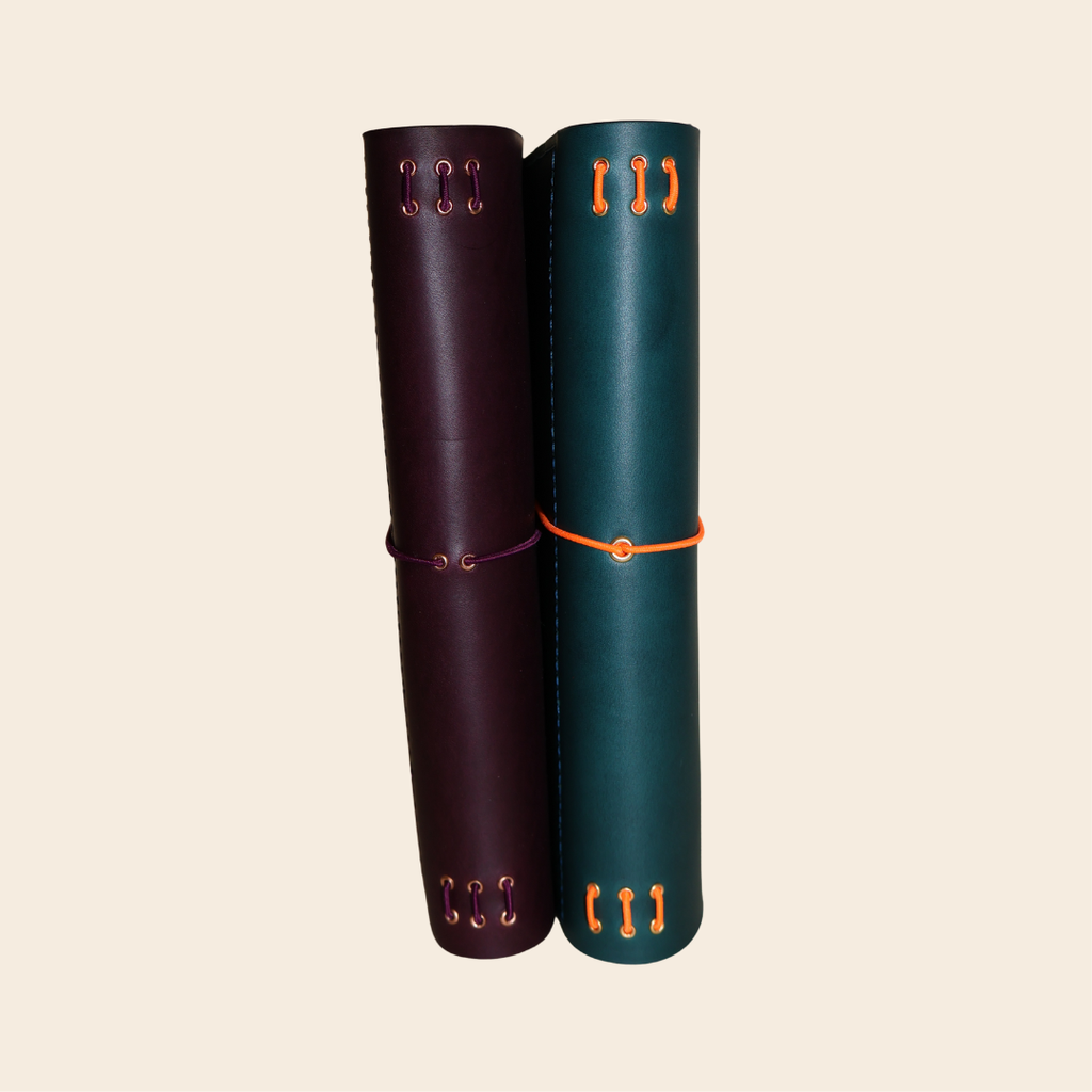 Two leather-bound books with decorative elements on a beige background