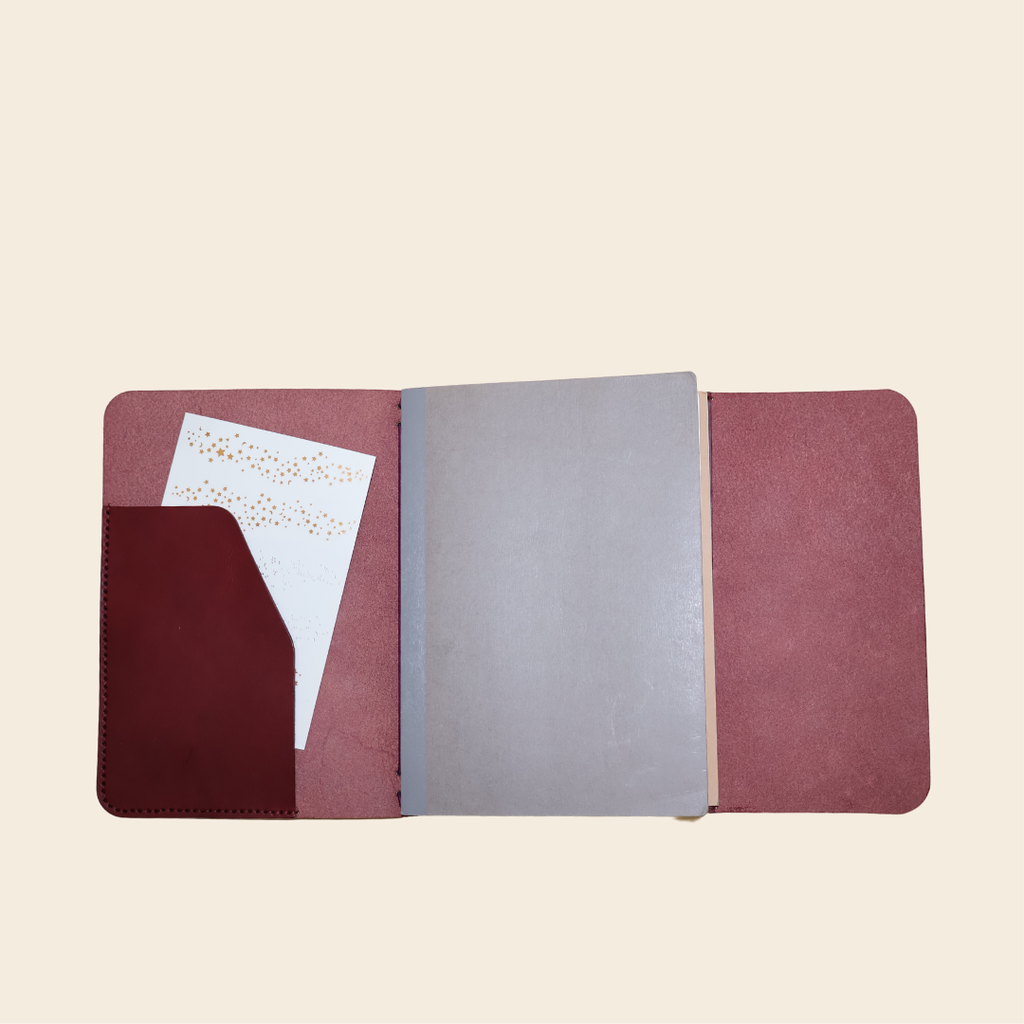 open leather journal with a Bordeaux interior and gray notebook on a beige background