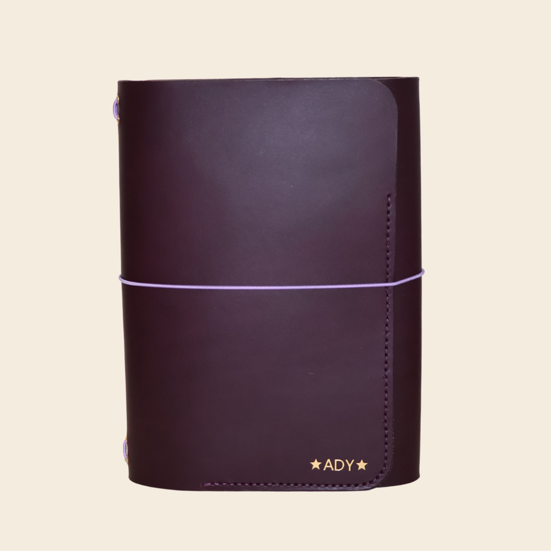 Purple leather notebook with gold foil on a beige background
