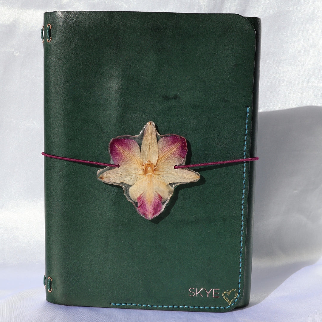 Green notebook with a dried flower on a white background
