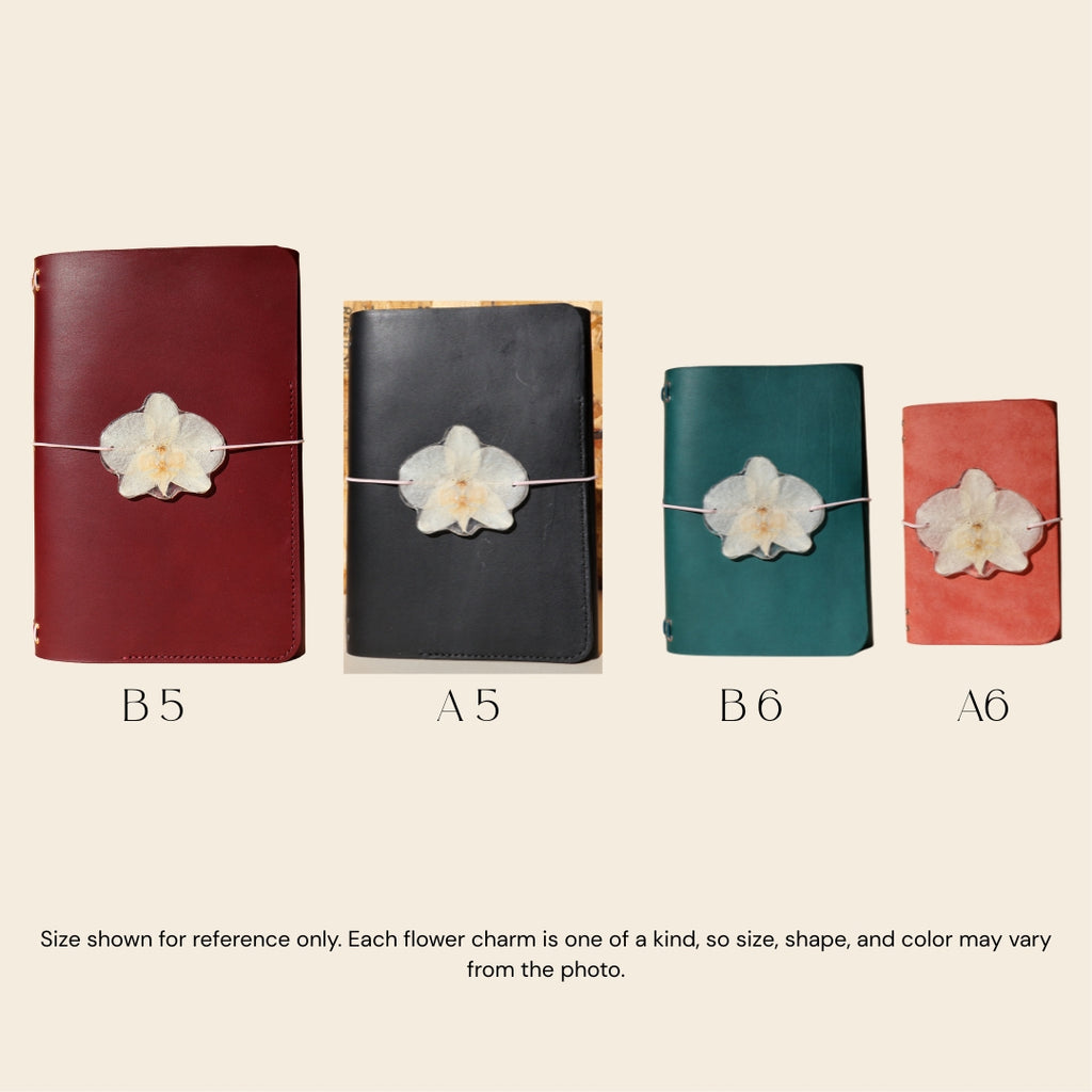 Four different sizes of notebooks with flower charms on a beige background