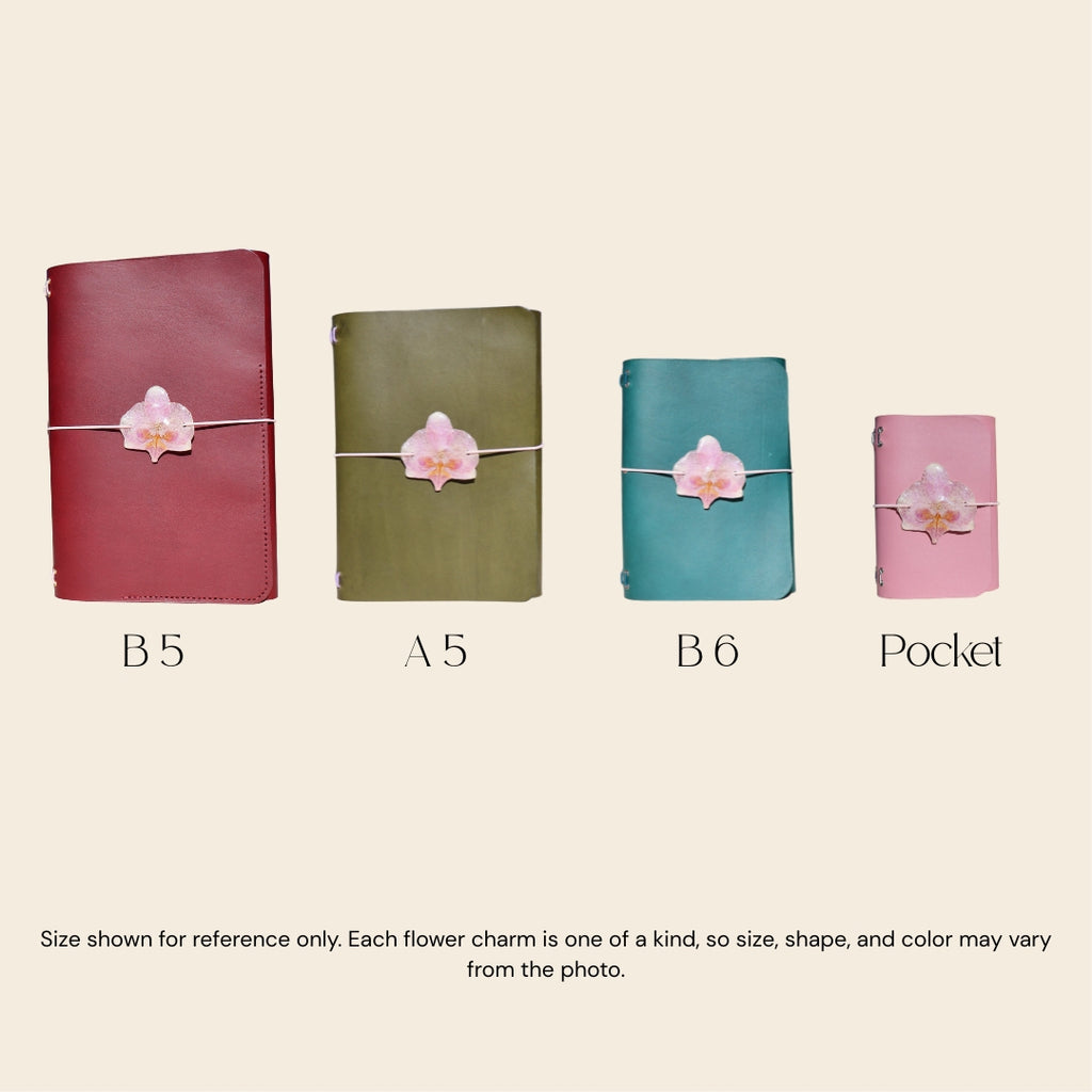 Four notebooks of different sizes with flower charms on a beige background