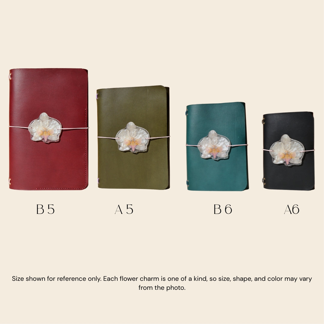 Four different sizes of notebooks with floral charms on a beige background
